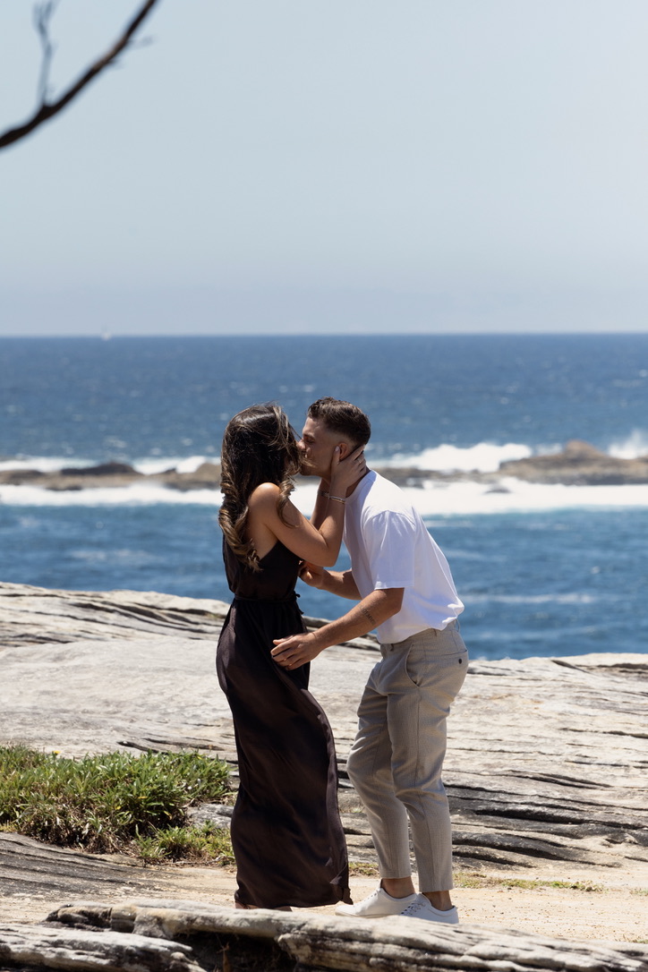 Isabella and David sharing a kiss by the ocean